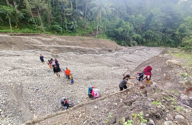 AKSES SULIT: Sejumlah siswa SDN 3 Kemuning menyeberangi Sungai Sempu dengan ditemani orang tua mereka ketika berangkat ke sekolah. (HENGKY RISTANTO/RADAR PACITAN)