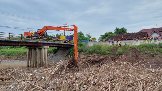 EVAKUASI: Warga bersama aparat dan relawan membersihkan bambrongan yang menyumbat Jembatan Jerohan, Desa/Kecamatan Balerejo, kemarin (3/2). (DIAN RAHAYU/JAWA POS RADAR CARUBAN)