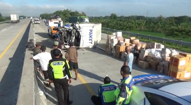 KILOMETER 382 A: Truk bermuatan paket terguling di Tol Ngawi-Kertosono, kemarin. (ASEP SYAEFUL BACHRI/JAWA POS RADAR NGAWI)