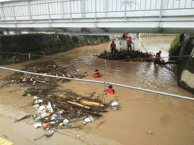 SEMPAT MELUAP: Petugas BPBD Kota Madiun membersihkan sungai di kawasan Buk Malang, Pilangbango, dari sampah kayu dan rumpun bambu. (RAHMA DWI LESTARI/JAWA POS RADAR MADIUN)