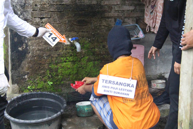 UPAYA HILANGKAN JEJAK: Reka adegan Anis yang mengenakan sebo membersihkan darah pada palu kayu. (ASEP SYAEFUL BACHRI/JAWA POS RADAR NGAWI)