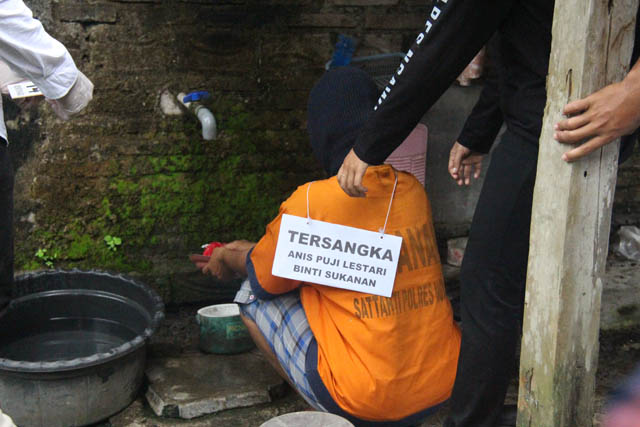 REKONSTRUKSI: Adegan Anis Puji Lestari membersihkan palu kayu yang digunakan membunuh suaminya. (ASEP SYAEFUL BACHRI/DOK. JAWA POS RADAR NGAWI)