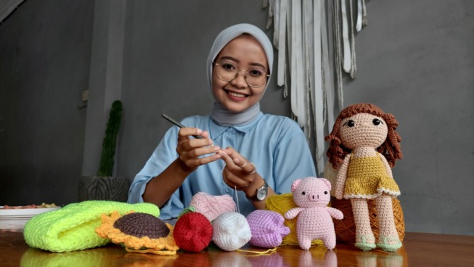 TELATEN: Hutami Widya Pratiwi saat merajut boneka amigurumi. (DIAN RAHAYU/JAWA POS RADAR CARUBAN)