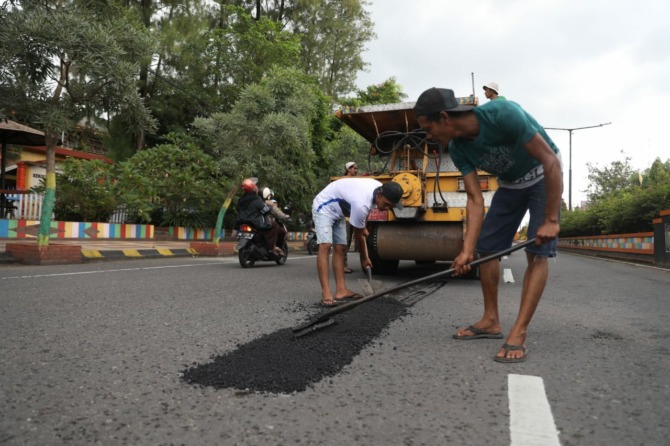 DEMI KENYAMANAN: DPUPR Kota Madiun mulai menambal aspal jalan yang berlubang kemarin (22/2). (BAGAS BIMANTARA/JAWA POS RADAR MADIUN)