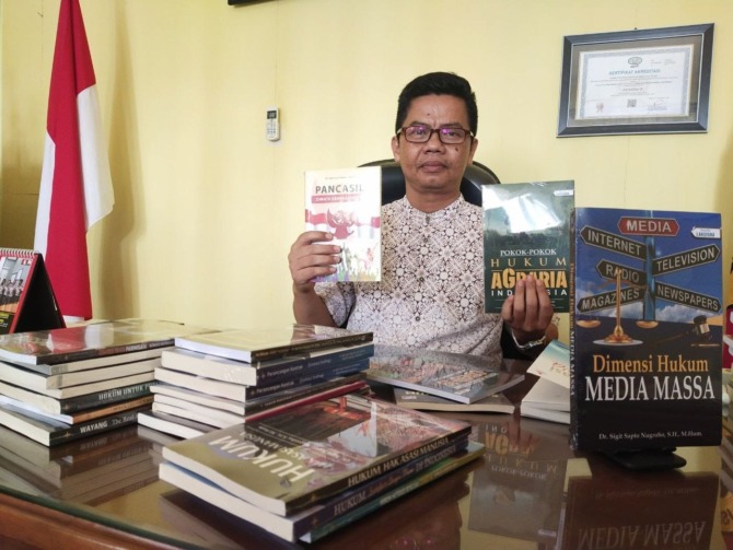 PRODUKTIF: Sigit Sapto Nugroho menunjukkan beberapa buku hasil karyanya. (RAHMA DWI LESTARI/JAWA POS RADAR MADIUN)