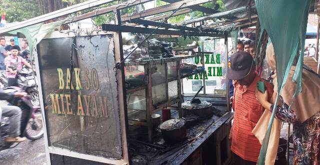 APES: Lukito mengguyur air gerobak bakso miliknya yang terbakar kemarin. (DAMKAR UNTUK JAWA POS RADAR PACITAN)