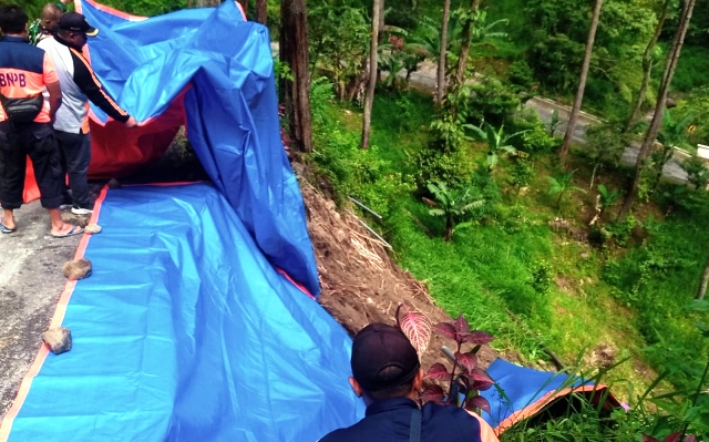 GOTONG ROYONG: Sejumlah petugas bersama warga memberikan penanganan darurat bahu jalan longsor kemarin. (APRILITA SARI/JAWA POS RADAR  MAGETAN)