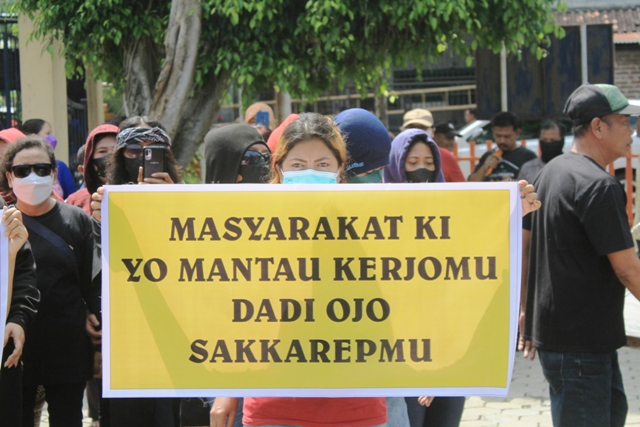 DEMO: Seorang pedagang Pasar Janti membentangkan poster bernada protes terkait pendapatan retribusi desa. (AJI PUTRA/RADAR PONOROGO)