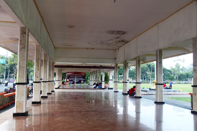 BAHAYA: Sejumlah warga duduk santai di tribun Alun-Alun Merdeka yang beberapa titik atapnya ambrol. (ASEP SYAEFUL BACHRI/JAWA POS RADAR NGAWI)