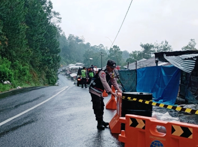 BAHAYA: Petugas memasang rambu peringatan longsor di Jalan Raya Sarangan- Cemorosewu. (BPBD MAGETAN UNTUK JAWA POS RADAR MAGETAN)