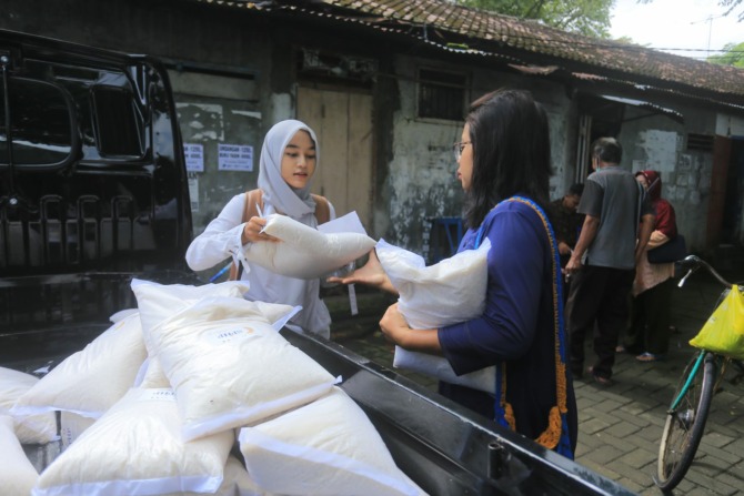 HARGA MIRING: Seorang warga saat membeli beras dalam operasi pasar yang digelar PDAU di Pasar Srijaya, Kota Madiun. (BAGAS BIMANTARA/JAWA POS RADAR MADIUN)