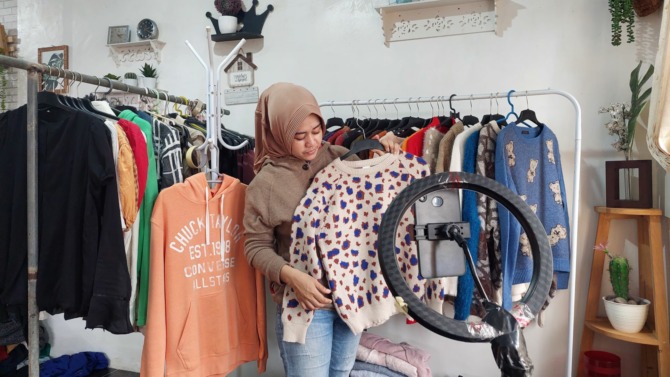VIEWERS SEPI: Seorang pengusaha thrifting sedang menjual produknya secara live streaming. (DIAN RAHAYU/JAWA POS RADAR CARUBAN)