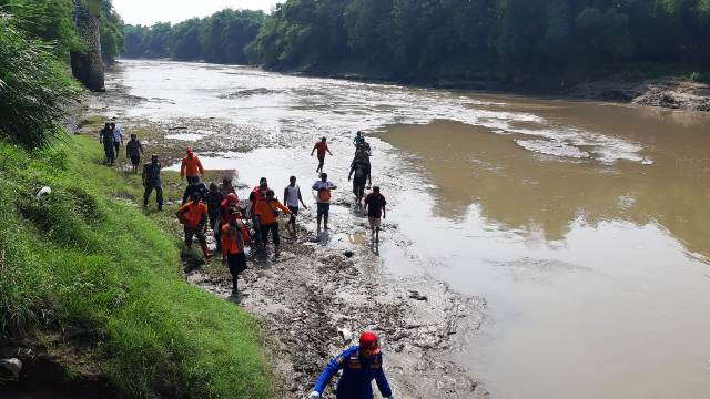 TEWAS TENGGELAM: Petugas gabungan mengevakuasi jasad Maksum yang tersangkut bebatuan aliran Bengawan Madiun kemarin. (ASEP SYAEFUL BACHRI/JAWA POS RADAR NGAWI)