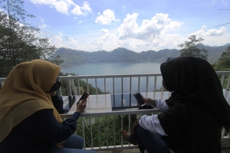 SANTAI: Wistawan yang berkunjung ke Ngambang Tirto Kencono dapat menikmati sunset sekaligus memandang luas Telaga Ngebel dari ketinggian. (AJI PUTRA/RADAR PONOROGO)