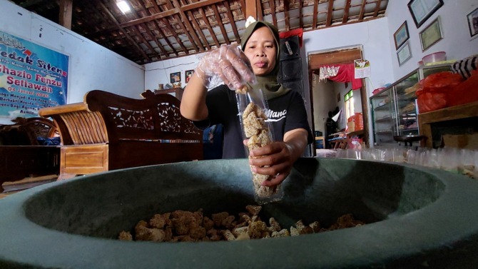 TRADISIONAL: Salah seorang karyawan Sumarlan sedang mengemas kue manco. (DIAN RAHAYU/JAWA POS RADAR CARUBAN)