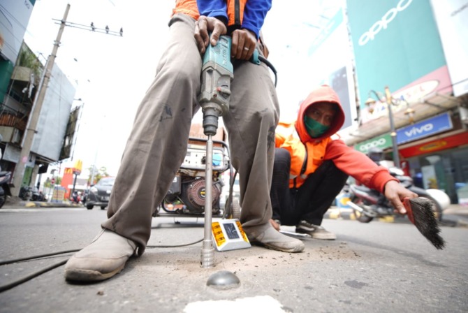 LAMPU MARKAH: Petugas Dishub Kota Madiun memasang road stud di Jalan Panglima Sudriman kemarin (5/4). (BAGAS BIMANTARA/JAWA POS RADAR MADIUN)
