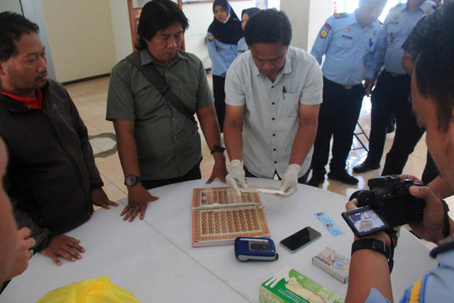 CEK: Petugas Lapas Pemuda Madiun memeriksa isi dalam jilid sampul Mushaf Alquran yang dibawa PWG. (LAPAS PEMUDA UNTUK JAWA POS RADAR MADIUN)