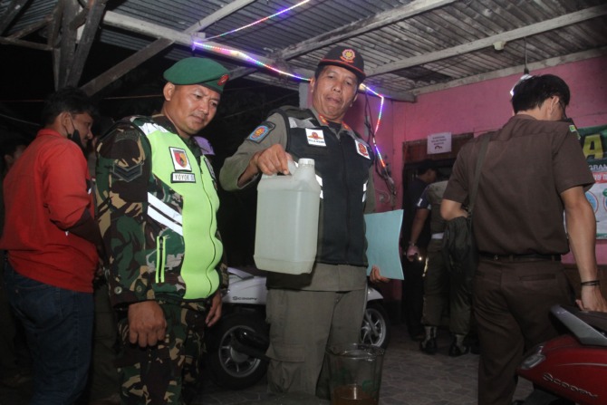 RAZIA: Satpol PP mengamankan puluhan botol miras berbagai merek dari sebuah toko variasi motor di kompleks Pasar Logam Jaya, Senin (15/5) malam. (BAGAS BIMANTARA/JAWA POS RADAR MADIUN)