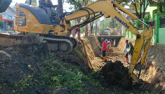 CEGAH BANJIR KOTA: DPUPR Pacitan menegerahkan alat berat untuk mengeruk material endapan di saluran air Jalan Maghribi, Mentoro, kemarin (22/5). (NUR CAHYONO/JAWA POS RADAR PACITAN)
