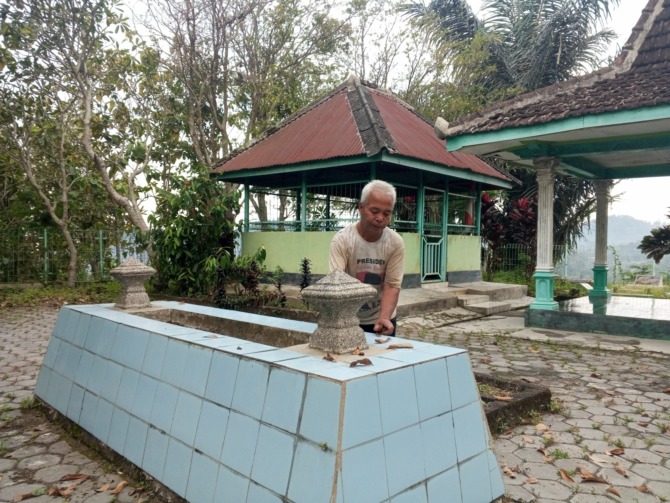 MANA YANG BENAR: Suyatno, membersihkan makam yang diyakini tempat peristirahatan terakhir bupati ketiga Ngawi, Adipati Kertonegoro. (ASEP SYAEFUL BACHRI/RADAR NGAWI)