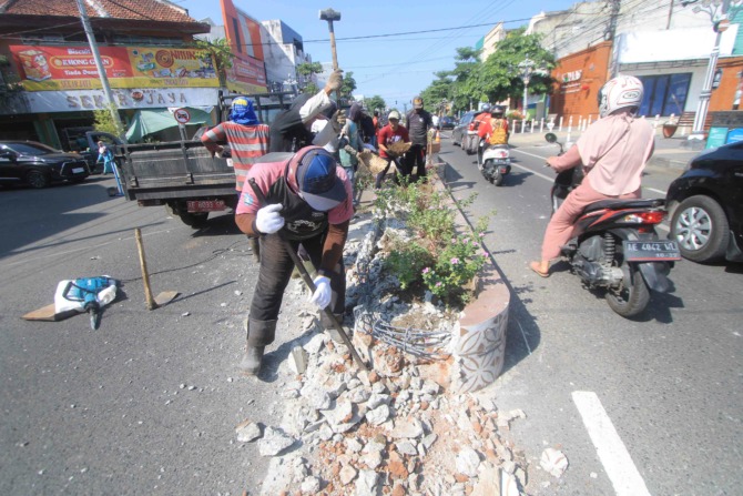 DIRATAKAN: Petugas DPUPKP bersama Dishub Ponorogo melakukan pembongkaran median Jalan HOS Cokroaminoto kemarin (14/6). (AJI PUTRA/JAWA POS RADAR PONOROGO)
