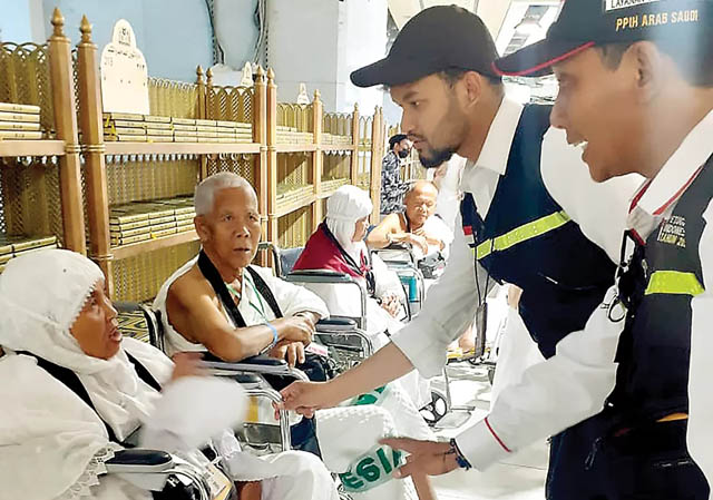 Petugas haji berkomunikasi dengan jemaah lansia yang menggunakan kursi roda di Masjidilharam.
