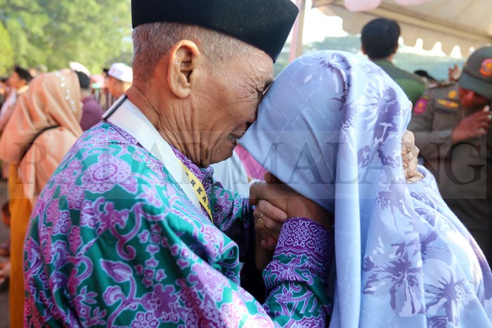 TANGIS BAHAGIA: Seorang calon jamaah haji (CJH) berpamitan kepada keluarga yang mengantarkannya di lapangan Rampal, Klojen kemarin (18/6).