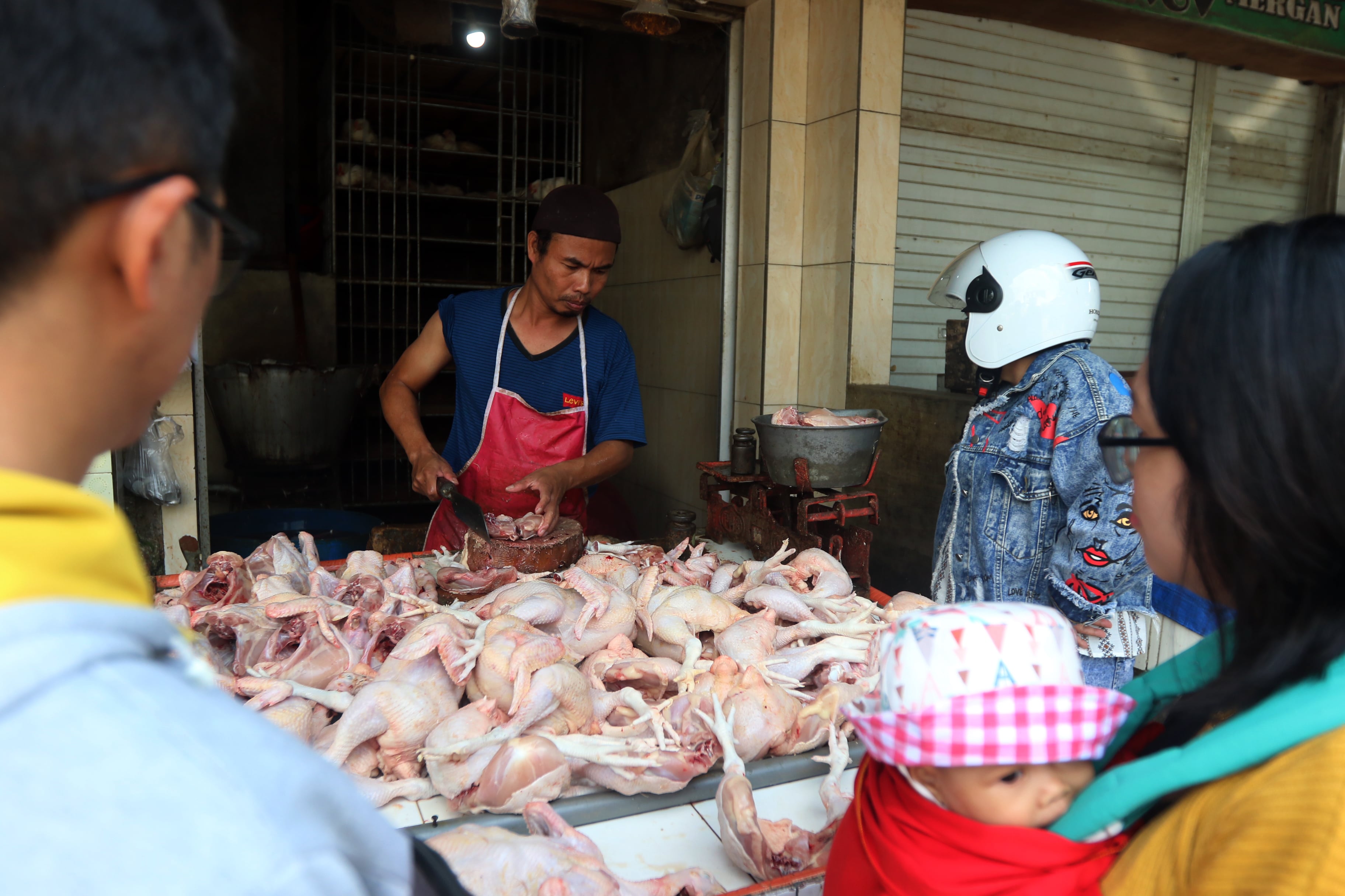 PEMBELI BERKURANG: Seorang pedagang ayam potong melayani pembeli di Pasar Mergan kemarin (30/6). Tiga hari belakangan tidak banyak lapak yang buka.