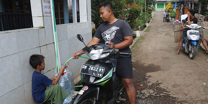Salah satu warga Desa Dengkol, Kecamatan Singosari, Kabupaten Malang mengisi air bersih ke dalam galon.