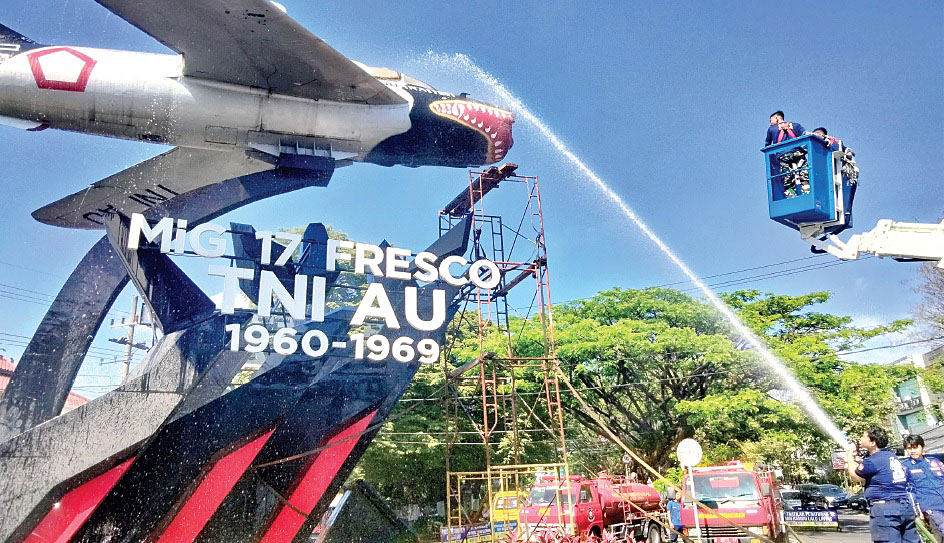 Petugas UPT Damkar Kota Malang menyemprotkan air ke monumen pesawat MIG 17 Fresco di Jalan Soekarno Hatta kemarin.