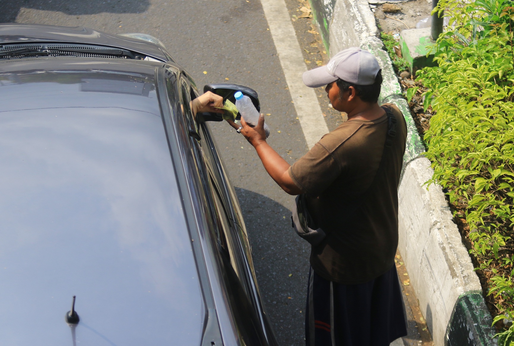 BANDEL: Seorang pengemis meminta belas kasihan dari pengendara mobil yang melintas di Simpang Tiga Sabilillah, Kecamatan Blimbing, kemarin siang. (suharto/radar malang)