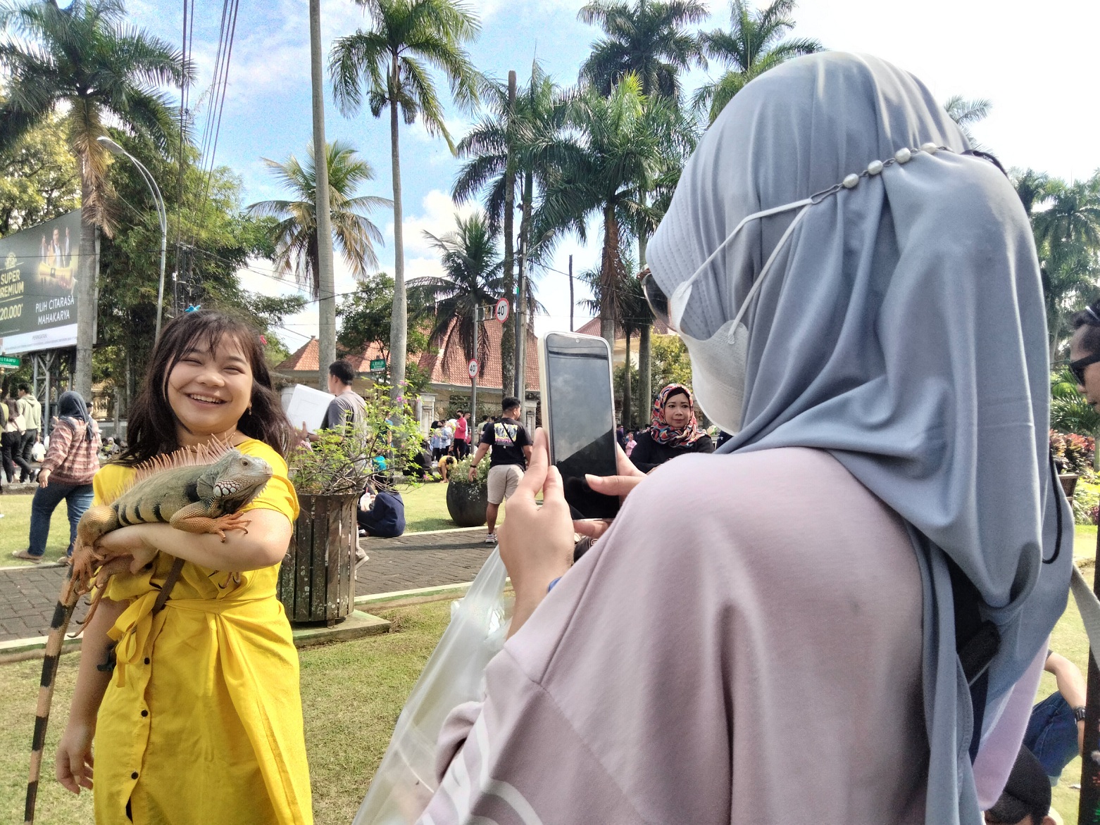 GEMBIRA: Seorang pengunjung CFD Ijen memotret temannya yang bermain dengan iguana milik Malang Reptile Keepers, kemarin pagi. (nabila amelia/radar malang)