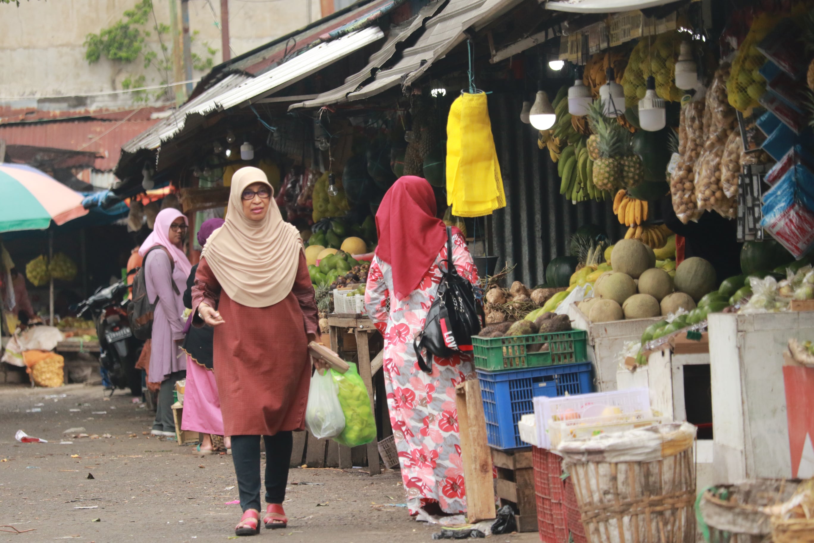 TUNGGU PERBAIKAN: Seorang pembeli melintasi lapak pedagang buah di Pasar Blimbing kemarin (17/7)