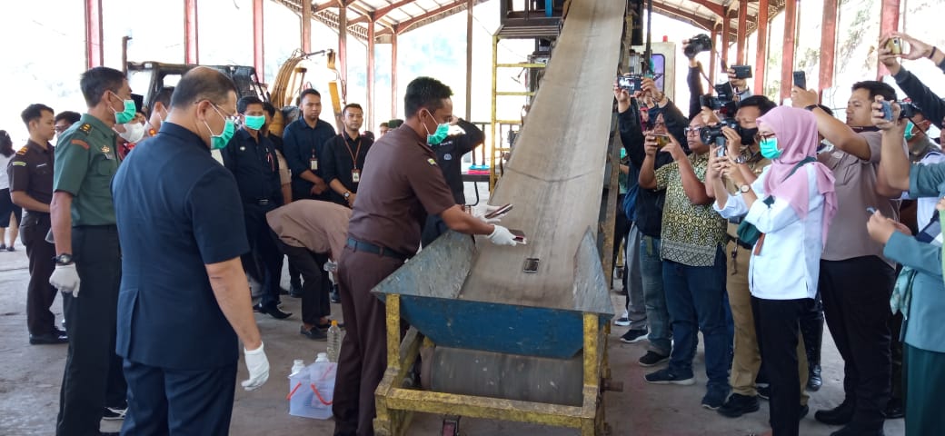 DIHANCURKAN: Kajari Kota Batu Agus Rujito meletakkan handphone barang bukti di atas conveyor untuk dimasukkan ke dalam mesin penghancur di TPA Tlekung (18/7).