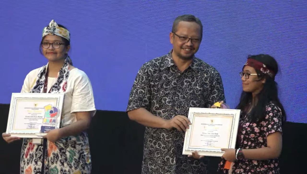 Indra Gunawan, SKM.,M.A,  Staf Ahli Perlindungan Perempuan dan Anak Kementerian PPPA RI menyerahkan penghargaan kepada Sekretaris Forum Anak Kota Malang Naura Athaya Syarif