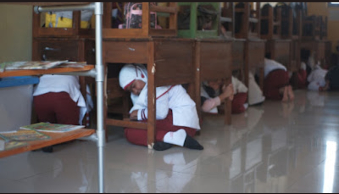 Siswa-siswi SD Sunan Giri Ngebruk, Kabupaten Malang tampak berlindung dari kemungkinan reruntuhan gempa di bawah meja-meja belajar.