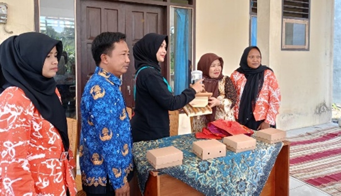 WARISAN LELUHUR: Penyerahan secara simbolis peralatan dan bahan pembuatan  batik cap dari bambu (batik cap) oleh Ketua tim pengabdian Dra Nurul Aini MPd kepada istri Kepala Desa Wonorejo, Nur Aini.