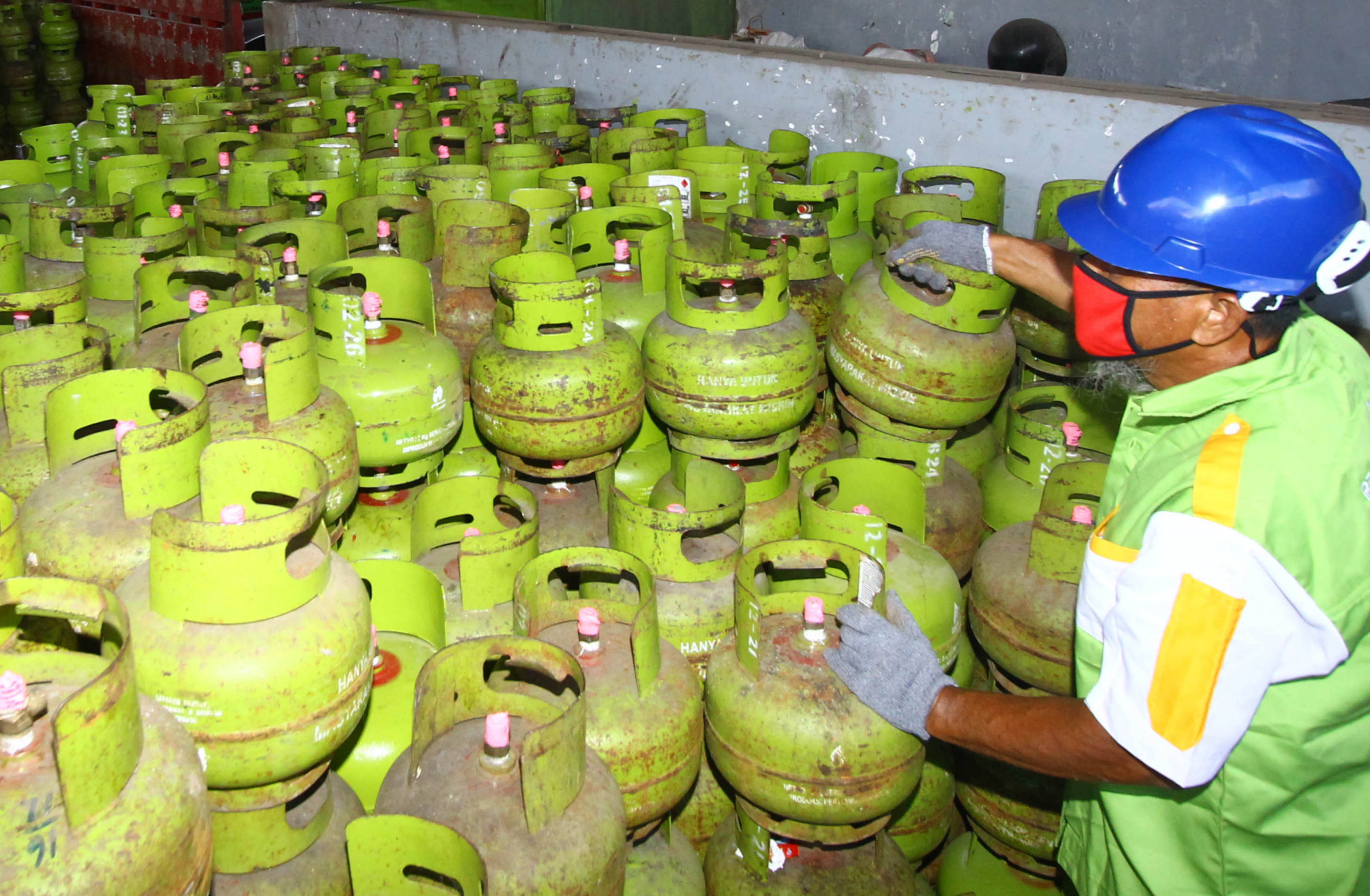 TAMBAH STOK: Petugas agen elpiji di Jalan Sunandar Priyo, Blimbing menata tabung gas berukuran 3 kilogram, kemarin siang. (Suharto/Radar Malang)