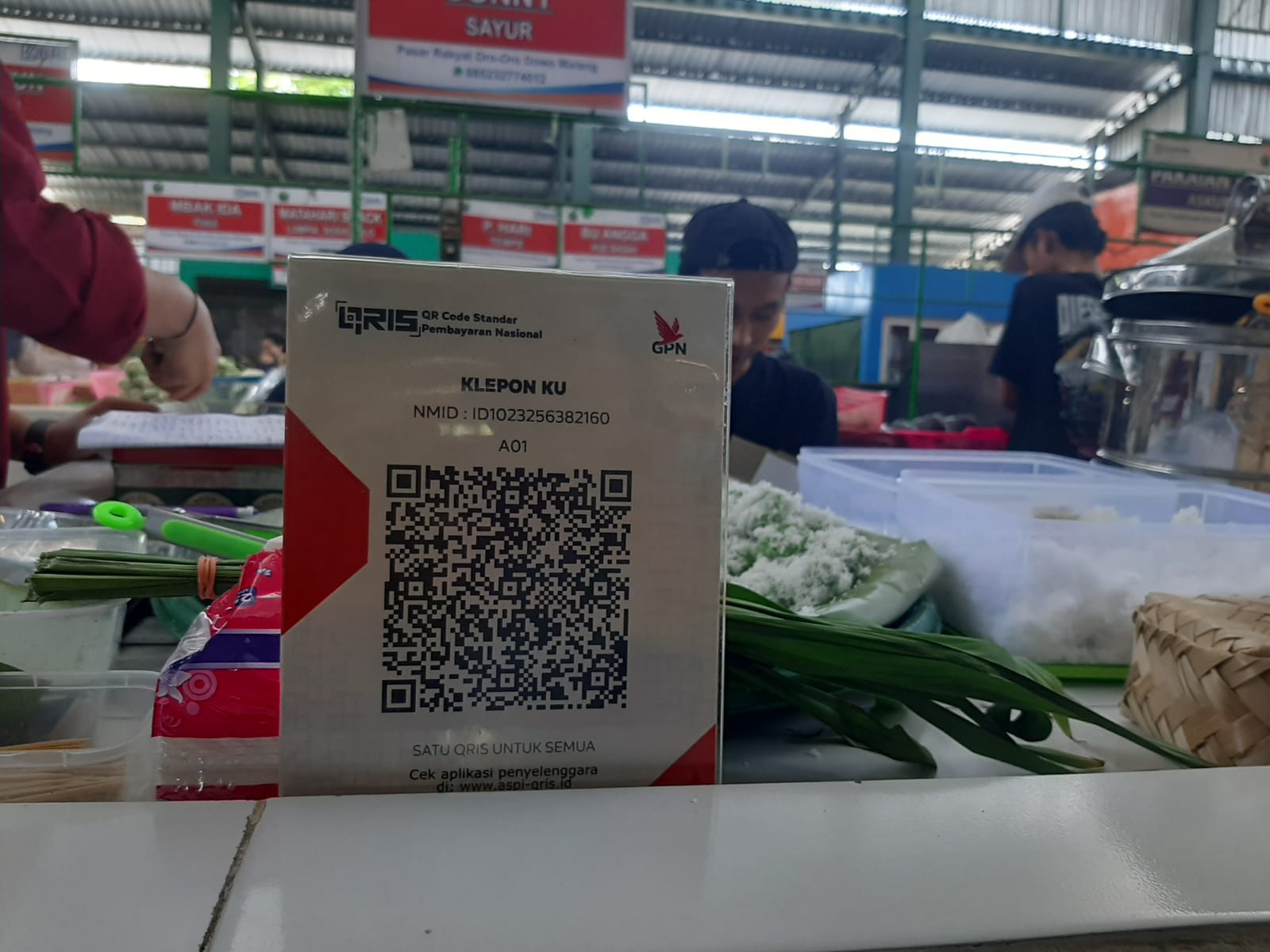 TINGGAL SCAN: Lapak pedagang di Pasar Oro-Oro Dowo, Klojen terpasang papan akrilik QRIS. (Durotul Karimah/Radar Malang)