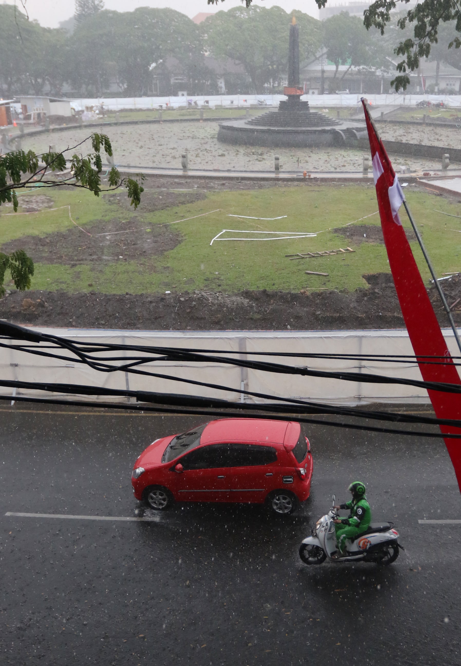 CUACA TAK MENENTU: Pengendara yang melintasi Alun-Alun Tugu diguyur hujan deras, kemarin (2/8).