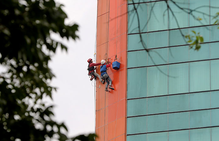 Pekerja membersihkan bagian luar gedung tinggi Aria Gajayana Hotel.