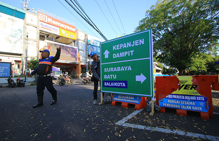 UJI COBA DULU: Petugas Dinas Perhubungan memasang rambu penunjuk arah dan water barrier yang membelah Jalan Merdeka Utara menjadi dua kemarin siang (11/8)