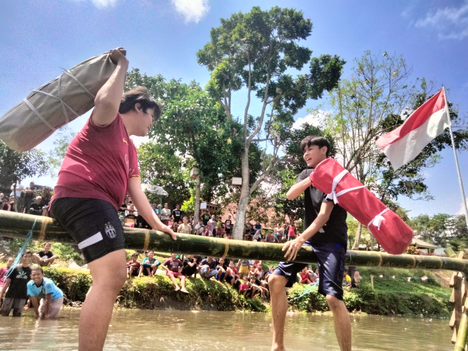 SEMARAK KEMERDEKAAN: Dua bocah saling pukul menggunakan guling di sungai kawasan Taman Edukasi Rolak Kedungkandang, kemarin (17/8).