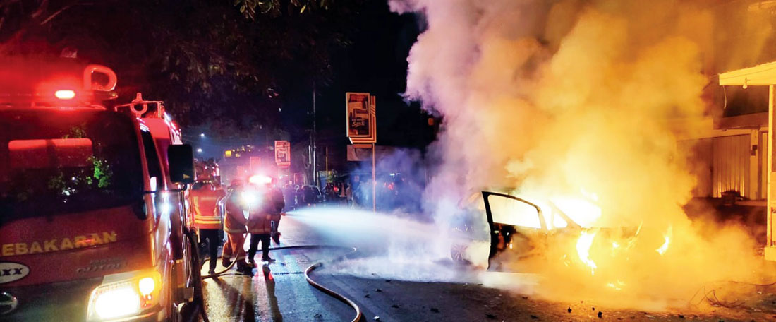 Petugas Damkar Kota Malang berupaya memadamkan api dari bagian mobil Honda Jazz yang terbakar dini hari kemarin.