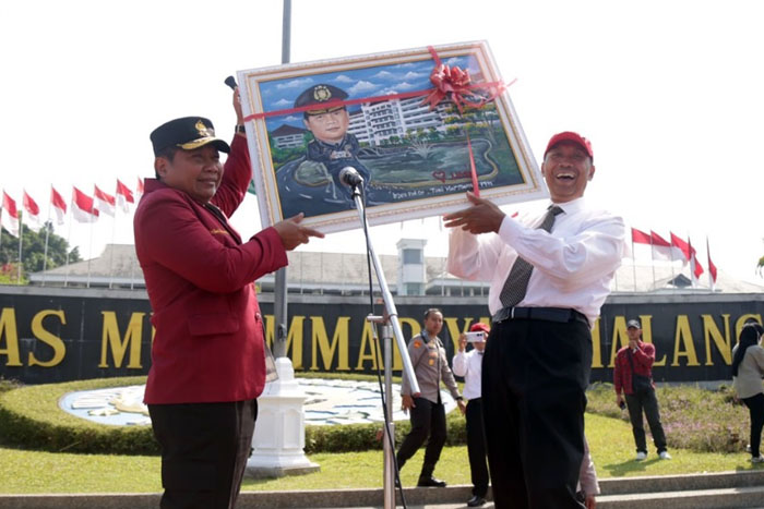 Kapolda Jatim Irjen Pol Dr  Toni Harmanto, MH menerima karikaturnya dengan latar kampus putih dari Rektor UMM Prof Fauzan