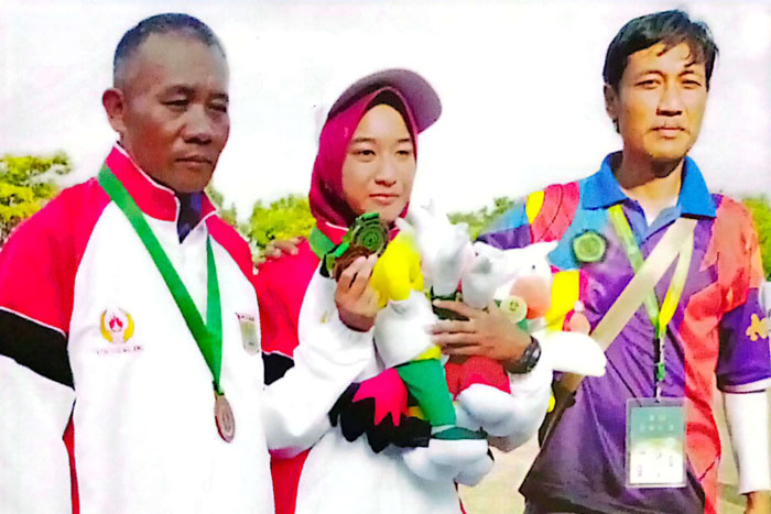Bintang Riviasasti Yudhistira (tengah) ditemani ayah dan pelatihnya usai memenangkan kejuaraan.