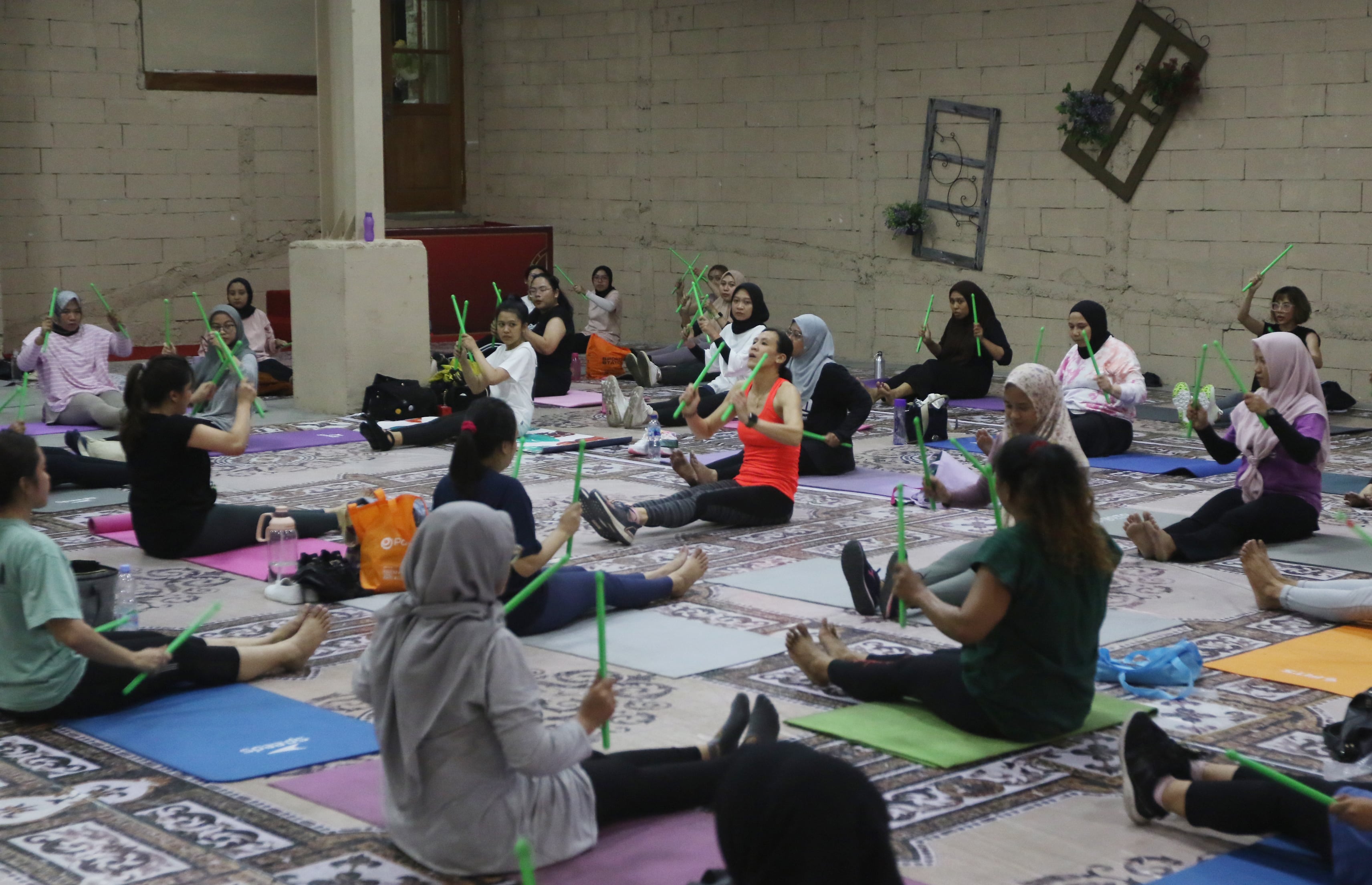 BANYAK DIMINATI: Para peserta duduk melingkar sembari menirukan gerakan instruktur yang duduk di tengah.