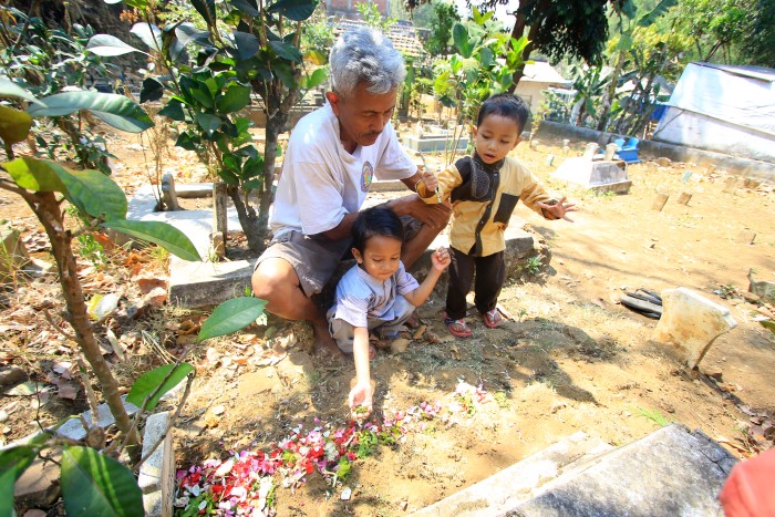 Hari Prasetyo bersama dua cucunya, nyekar ke makam Radina, putri Hari yang korban meninggal Tragedi Kanjuruhan Malang.