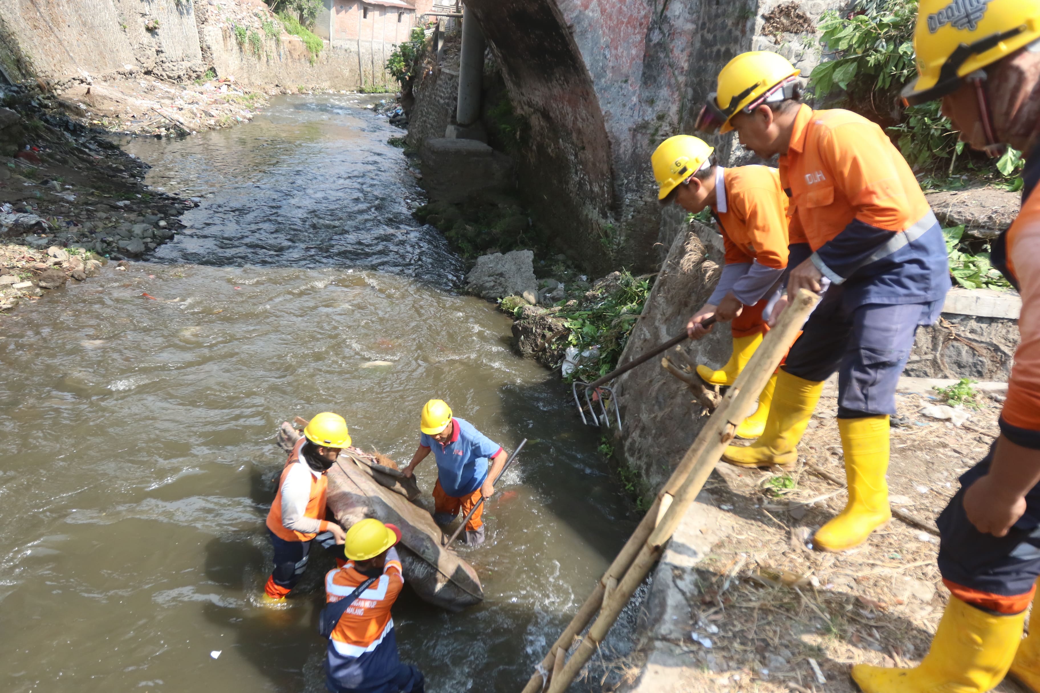 BERSIH-BERSIH: Tim gabungan dari DLH Kota Malang mengangkat sampah kasur bekas di sungai Ngaglik, Kecamatan Sukun, kemarin (9/10).