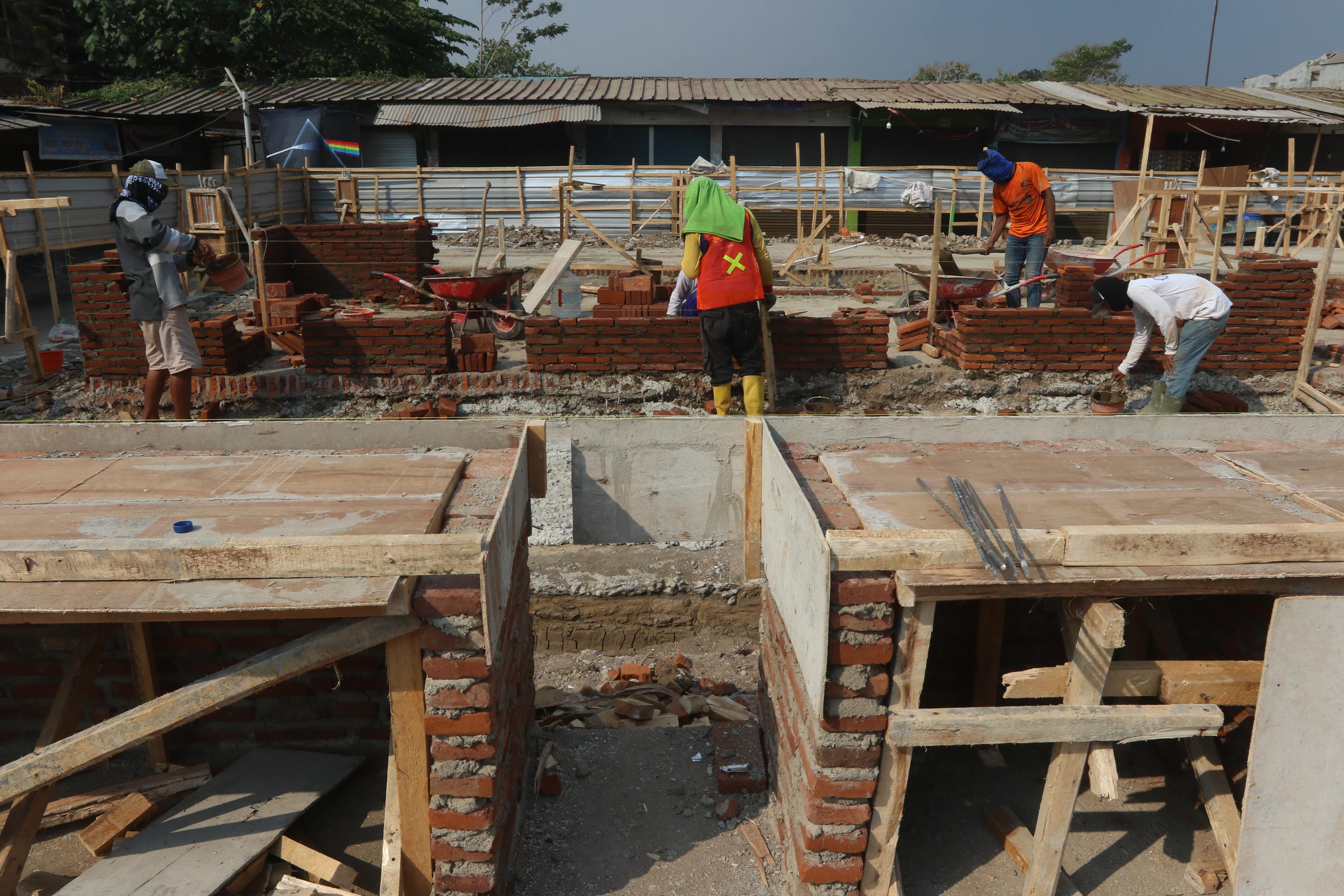 REVITALISASI: Para pekerja memasang batu bata untuk bedak para pedagang kemarin (10/10). Revitalisasi Pasar Madyopuro diperkirakan rampung akhir Oktober nanti.